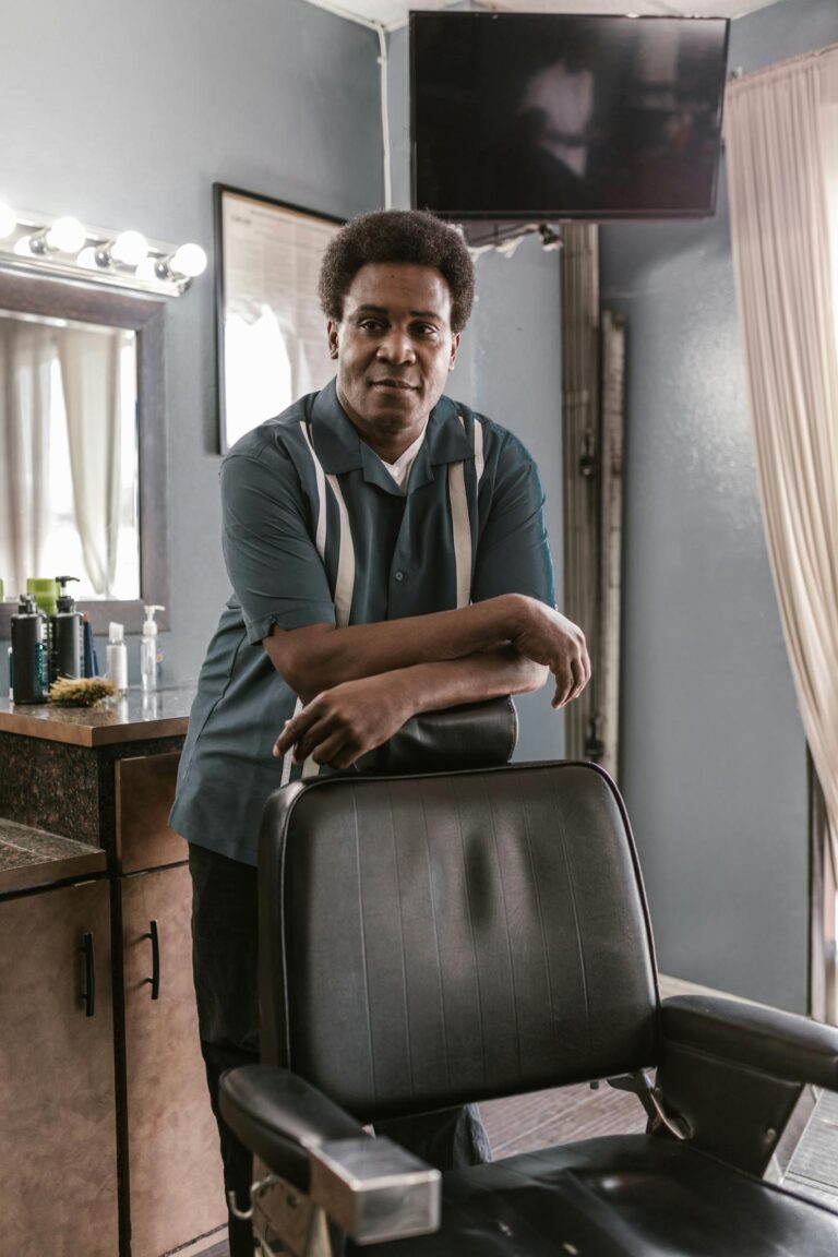 African American barber standing by a vintage chair in a traditional barbershop