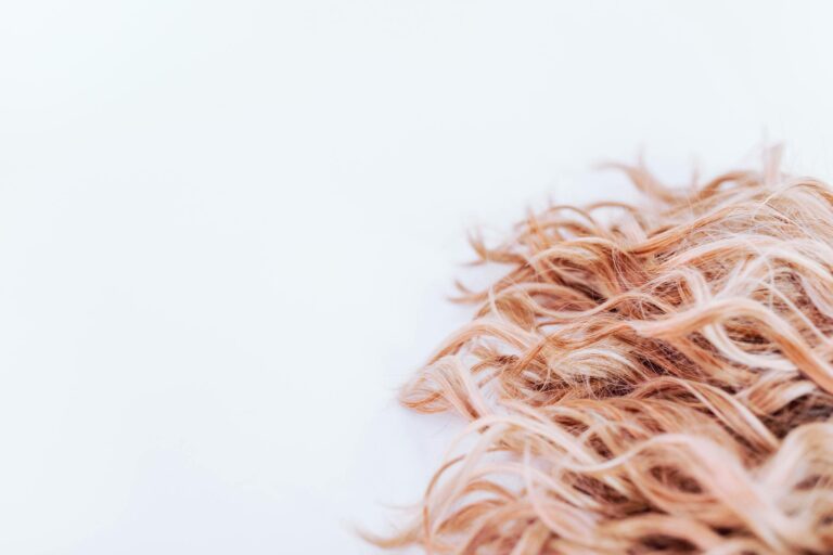 Detailed close-up of wavy blonde hair texture on a light background, showcasing elegance and style.